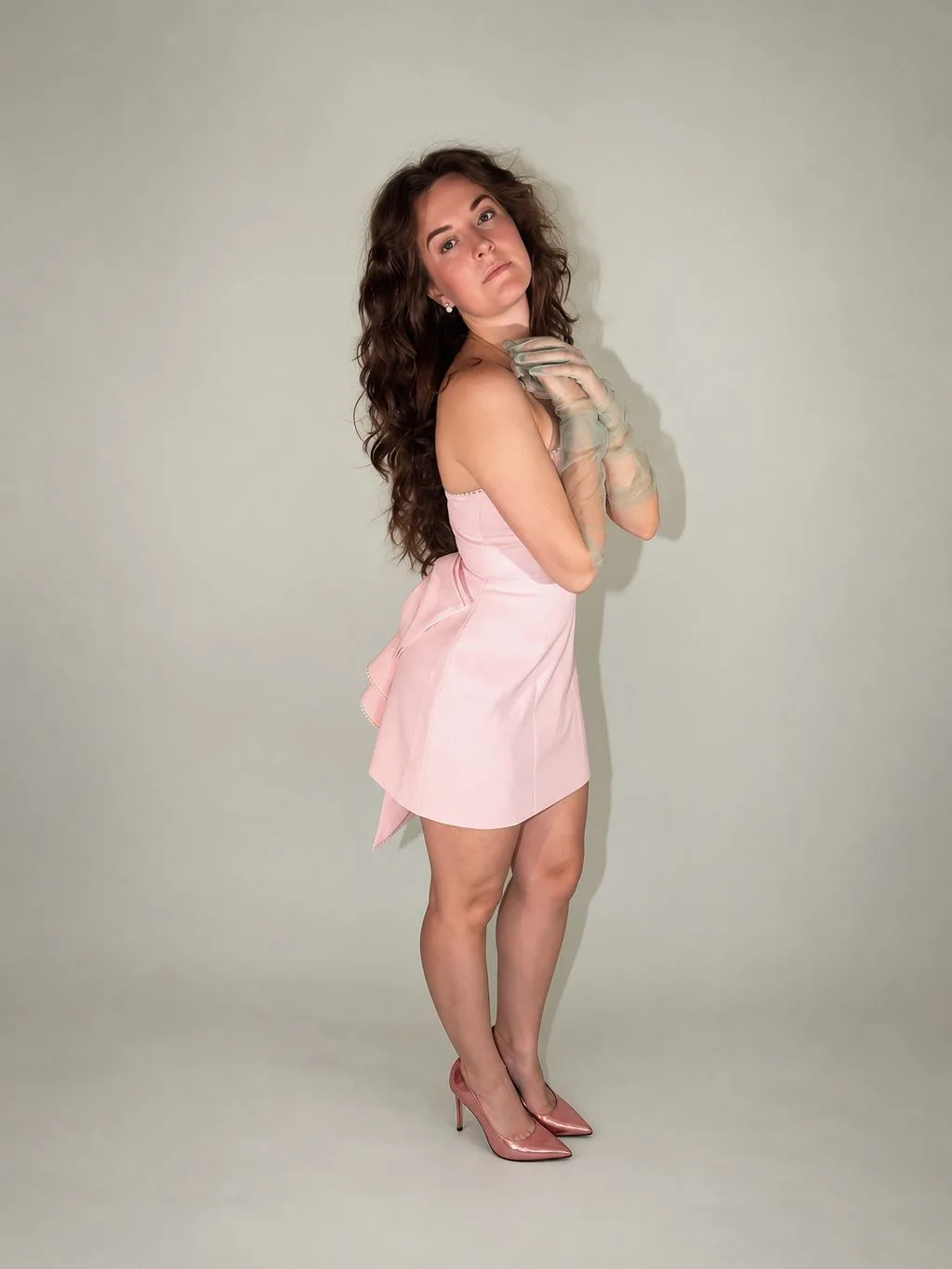 A full-body portrait in a pale pink dress with sheer sage-green gloves.