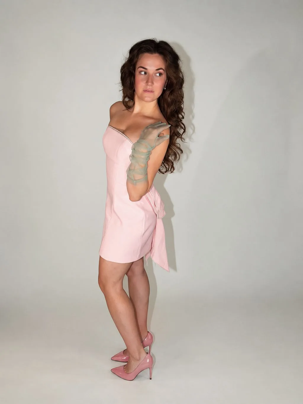 A full-body portrait in a pale pink dress looking to the side.
