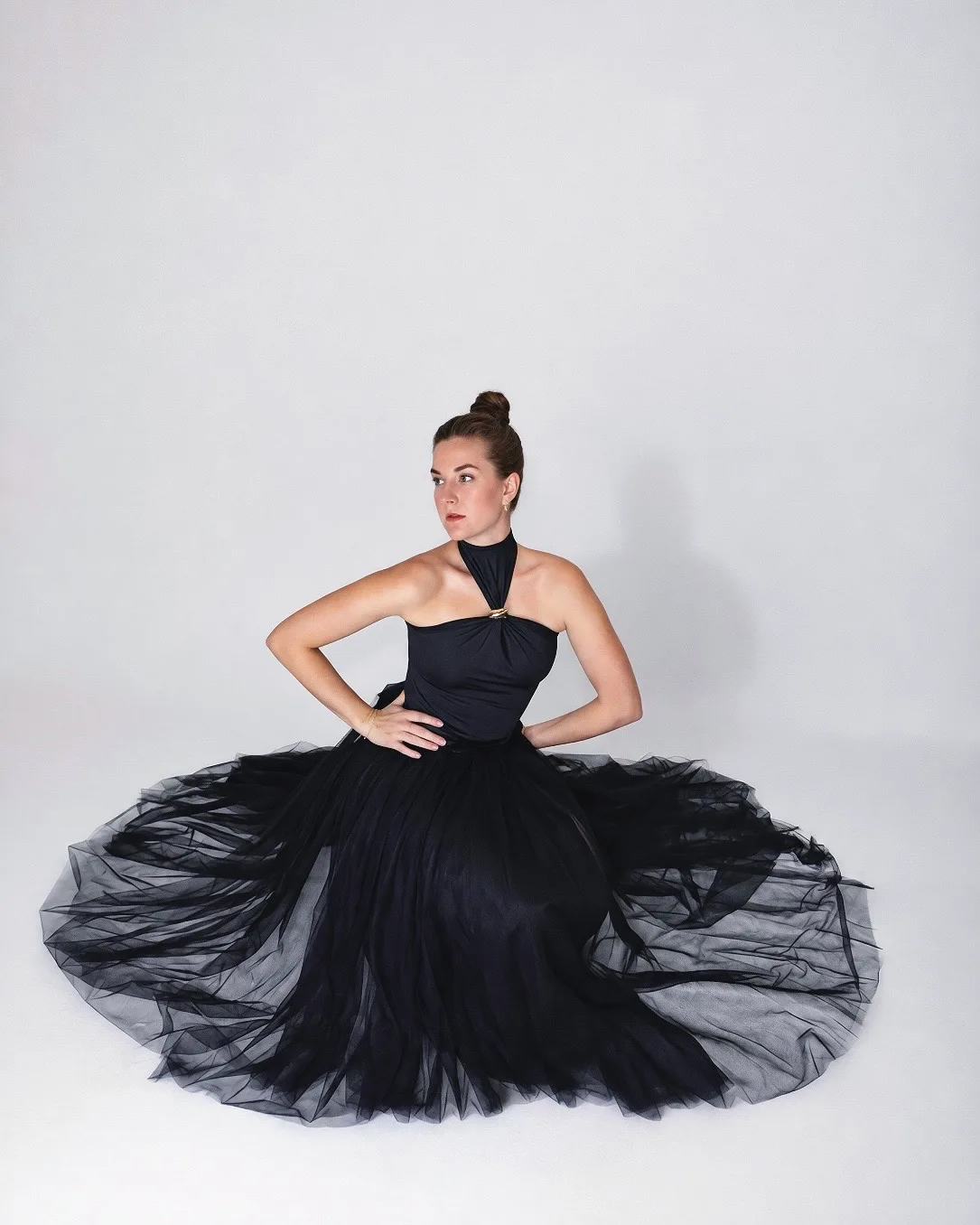 Seated with hands on hips, the black tulle skirt fanned out in a circle on the floor.