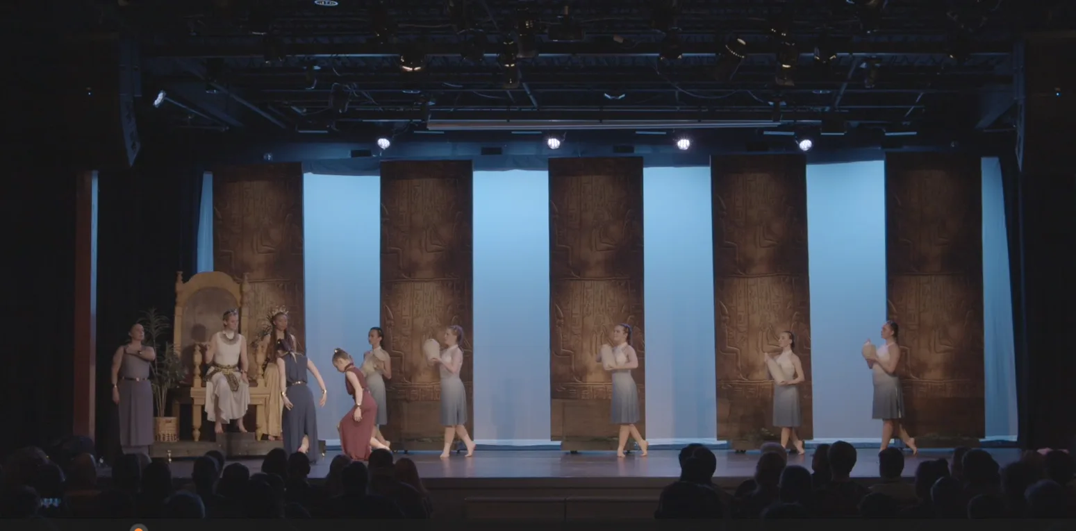 Wide view of the palace set with the throne at stage left and dancers in white.